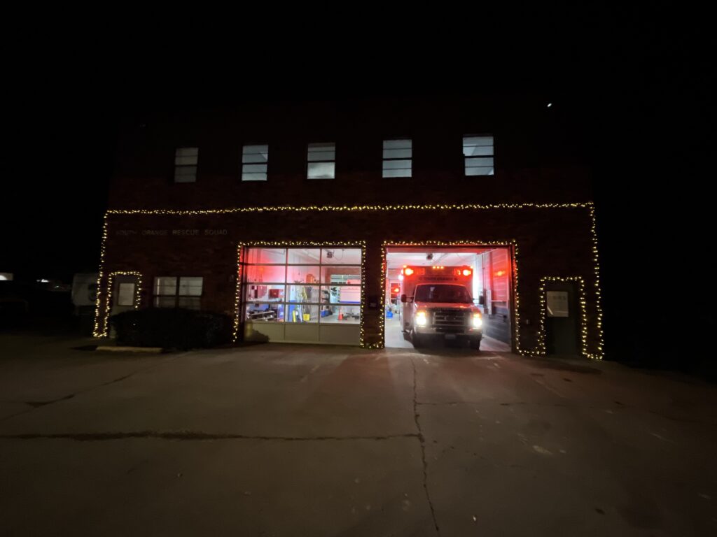 This photo by SORS Member Soorya Vasan shows the front of SORS’ station in downtown Carrboro lit up for the season with fairy lights. The second-story windows are lit, as are both ambulance bays. The door to the right-side bay is open to reveal one of our ambulances with its lights all aglow.