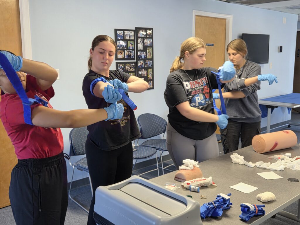 Four young women in a recent SORS Stop the Bleed training practice putting tourniquets on themselves and each other. 
